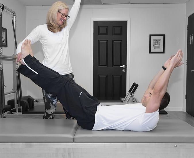 Pilates teacher cueing a fit male client during a private Pilates session